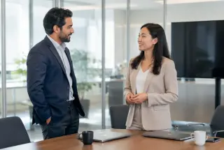Deux collègues discutent cordialement dans un bureau avant une réunion professionnelle.